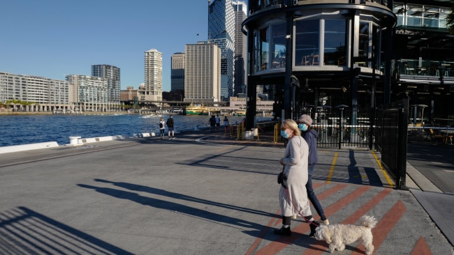 Two Sydneysiders wear face masks while walking near the harbour on Saturday. Photo: James D. Morgan/Getty Images