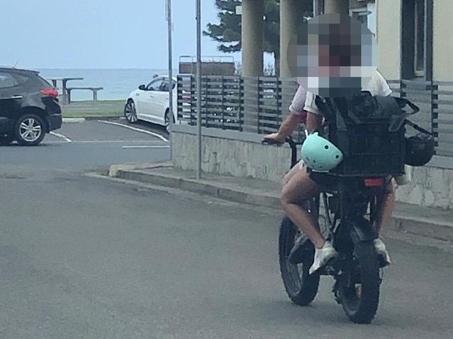 Two teenagers, with their helmets dangling, on an e-bike near Queenscliff Beach. Picture: Jim O'Rourke