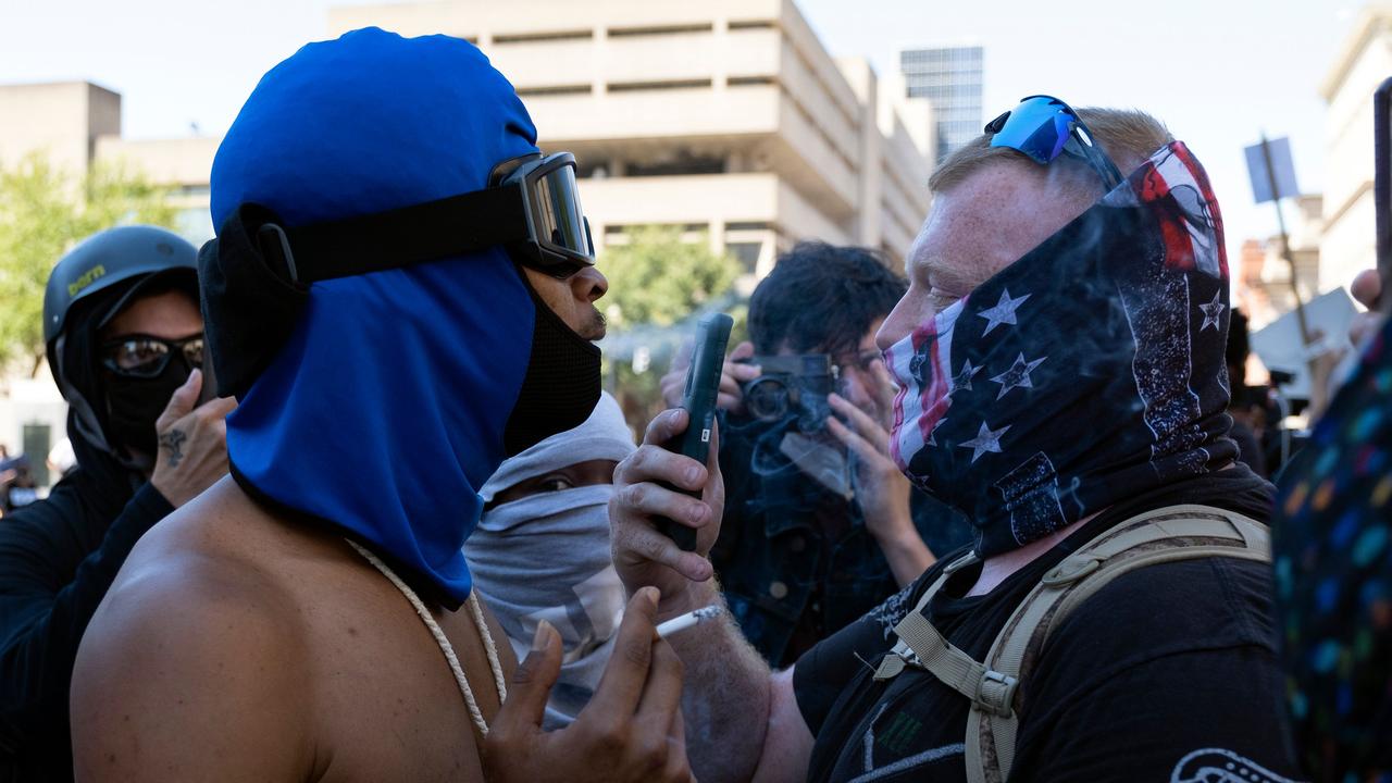 A counter-protester blows cigarette smoke in the face of a patriot militia member as he marches in support of local police officers in front of the Louisville, Kentucky, courthouse on September 5, 2020. Picture: Jeff Dean