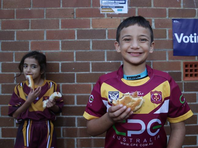 Get in quick on Saturday — just like Alyssa Thompson, 6, and Alessandro Thompson, 7, at the NSW Election earlier this year — to secure your democracy sausage. Picture: Craig Wilson