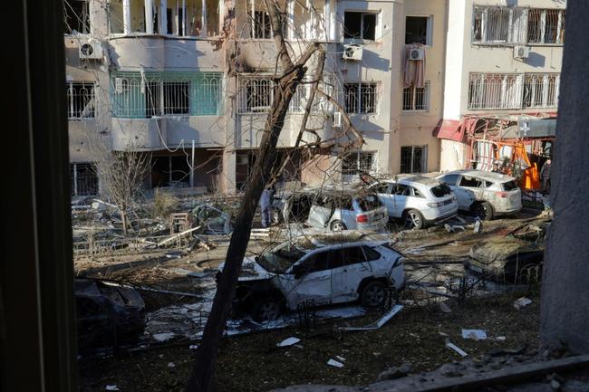 Local residents inspect damage to a residential building and cars following a missile attack in Odesa