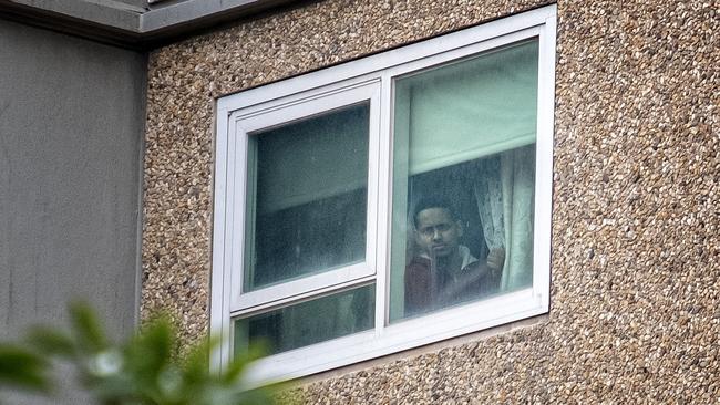 Resident Abdi Abrihim watches as authorities enter the Flemington Housing Commission flats on Sunday. Picture: Luis Enrique Ascui