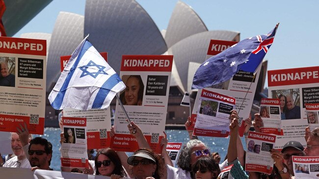 Members of the Australian Jewish community hold banners and placards in front of Sydney Opera House.