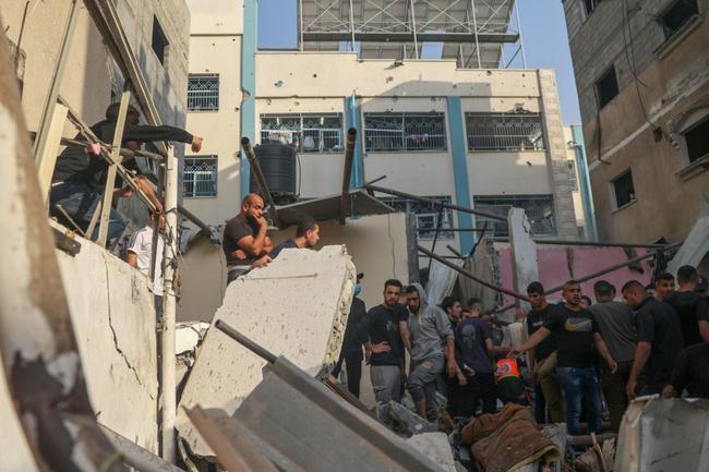 Palestinians search for casualties in the rubble of a house destroyed in an Israeli strike on Rafah, in the southern Gaza Strip