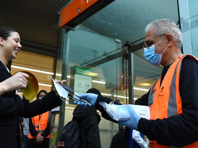 NSW Transport workers hand out face masks at Town Hall rail station in Sydney, Thursday, May 6, 2021. In Sydney, the Blue Mountains, the Central Coast and Illawarra, masks will be compulsory at all public indoor venues and on public transport from 5pm on Thursday while visitors in homes will be capped at 20. (AAP Image/Joel Carrett) NO ARCHIVING