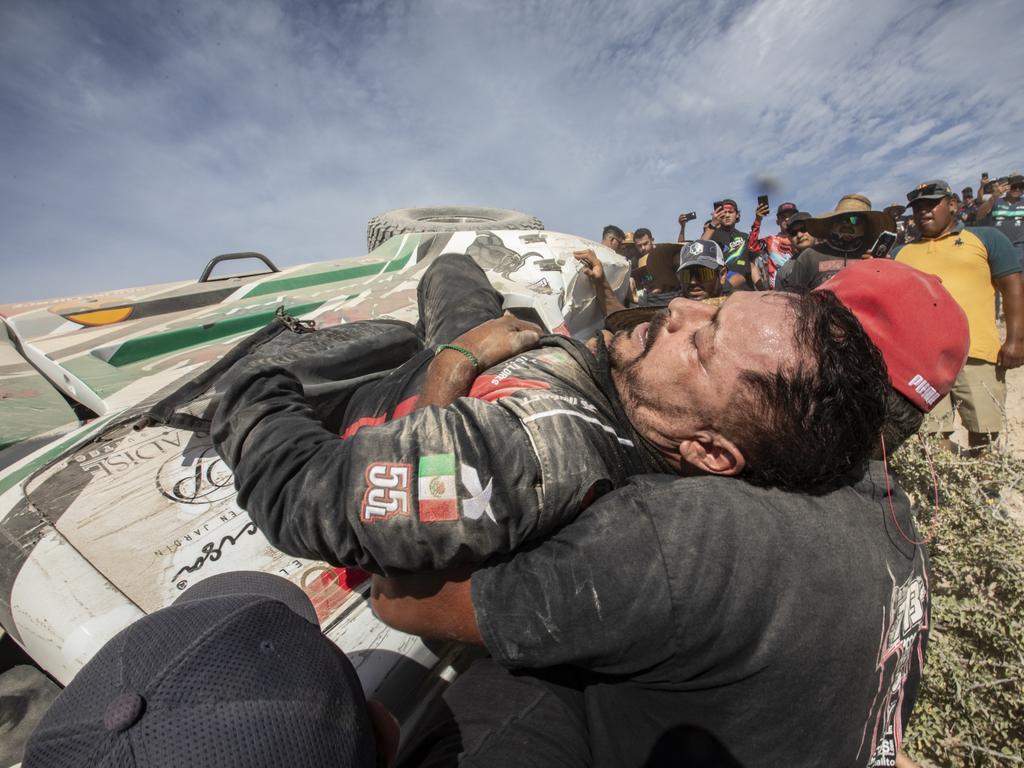 Driver Mayo Flores is helped by a fan to get out of his overturned car during the Baja 1000 2023 in La Paz, Mexico. Picture: Alfredo Martinez/Getty Images