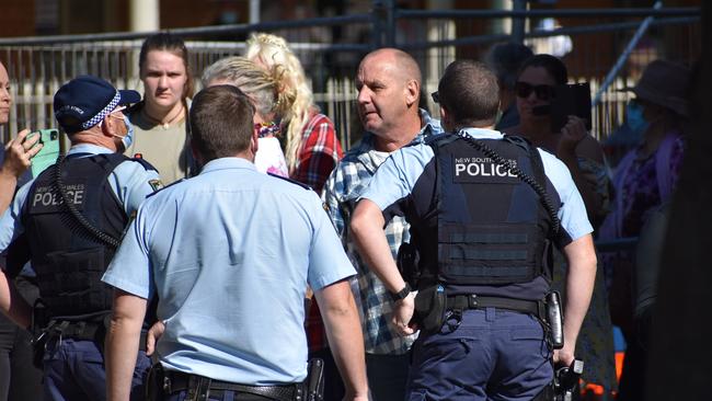 A man is spoken to by police at an anti Covid-law protest in Grafton. Picture: Jenna Thompson