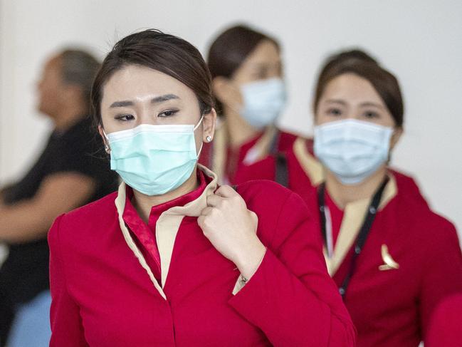 People wearing protective face masks to protect themselves from Coronavirus are seen at Brisbane International Airport in Brisbane, Friday, January 31, 2020. The World Health Organisation has declared the coronavirus outbreak a global emergency. (AAP Image/Glenn Hunt) NO ARCHIVING