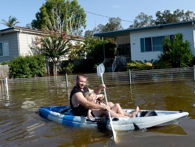 Residents of Geoffrey Road in Chittaway Bay, take to the flooded street in water craft. Photo Jeremy Piper