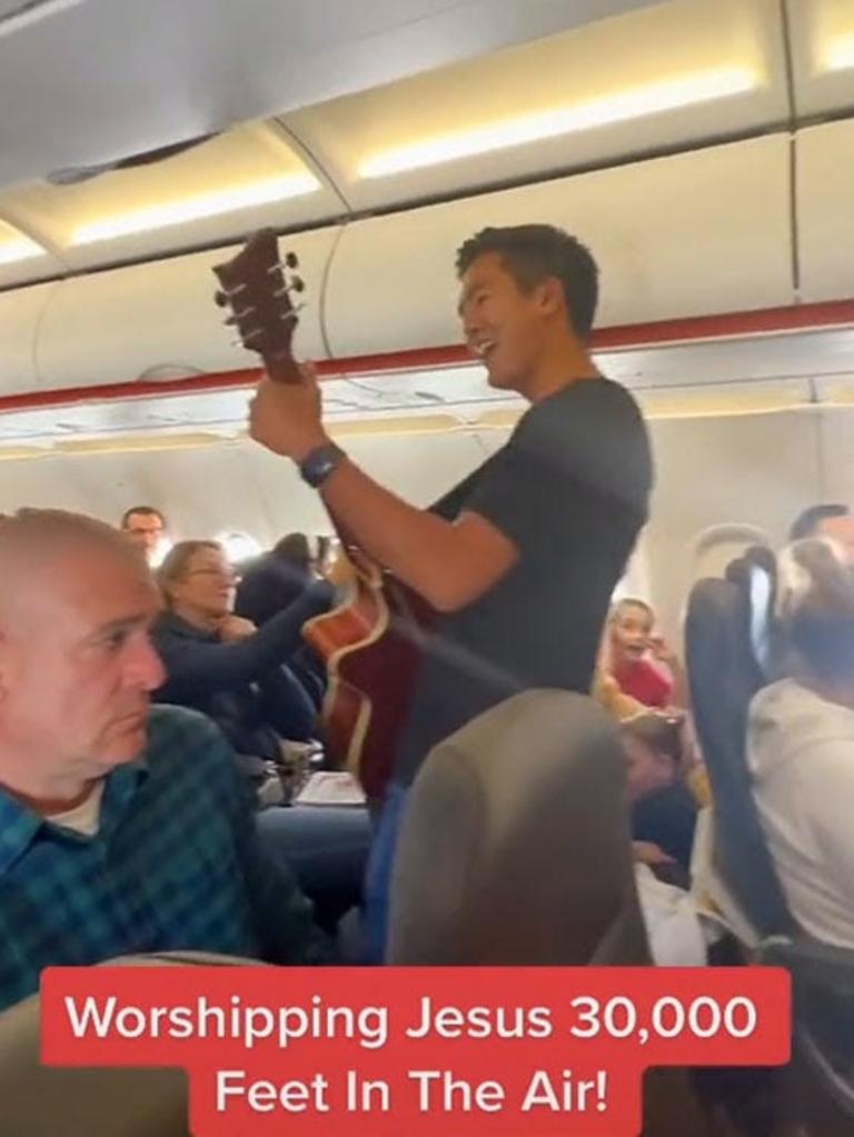 The man playing a guitar and singing Christian songs on board the plane.