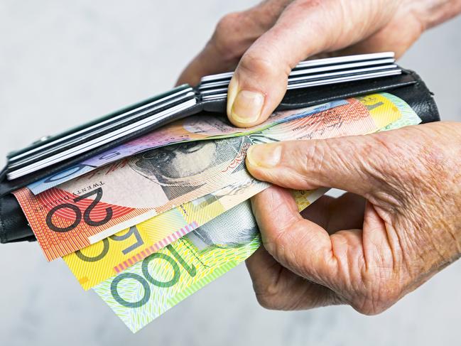 AUSTRALIAN CURRENCY/ DOLLARS/  PICTURE: istock Close-up, senior female hands taking Australian banknotes (cash, currency) from purse containing many credit cards.  Horizontal, studio, copy space.