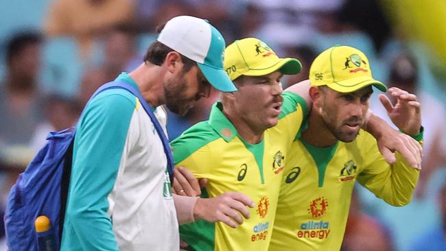 David Warner is assisted from the field after he suffered a groin injury at the SCG