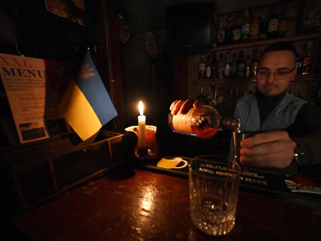 A bartender pouring a drink by candlelight during a power cut at a bar. In order to avoid a total blackout, the national operator has implemented scheduled power cuts in the capital. Picture: AFP