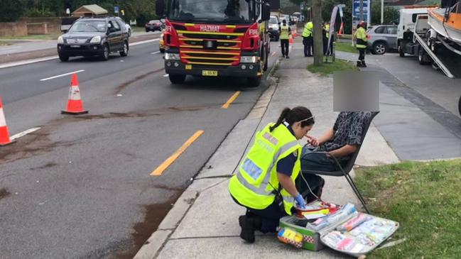 A NSW Ambulance paramedic assesses a man after a three-car crash on Warringah Rd in Forestville on Thursday afternoon. Picture: Jim O’Rourke