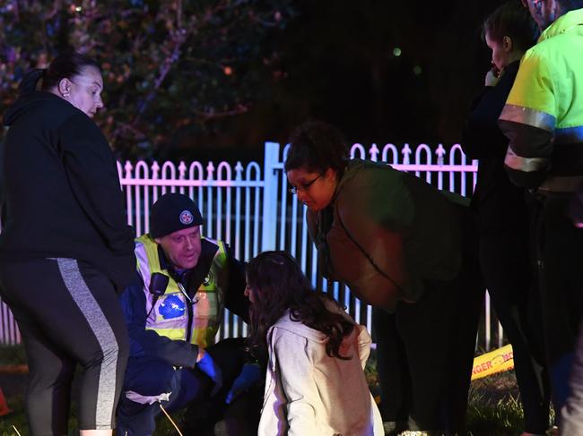 A paramedic attends to a woman who collapsed at the scene. Picture: Gordon McComiskie