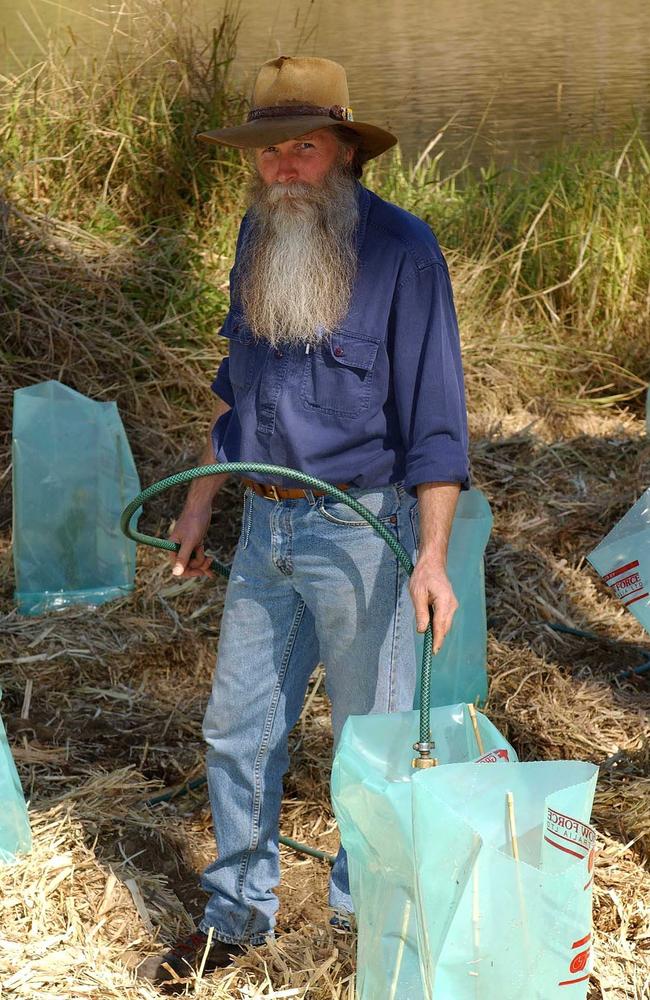 Renowned horticulturist and conservationist Bruce Tinworth watering plants near a river in Ipswich. Picture: Carinity