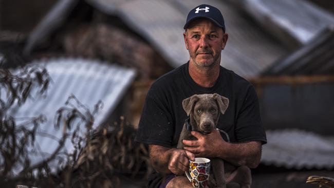 Shane Leahy with his dog Ash in front of the remains of his home lost in the Kangaroo Island bushfires in January. Picture: Sean McGowan