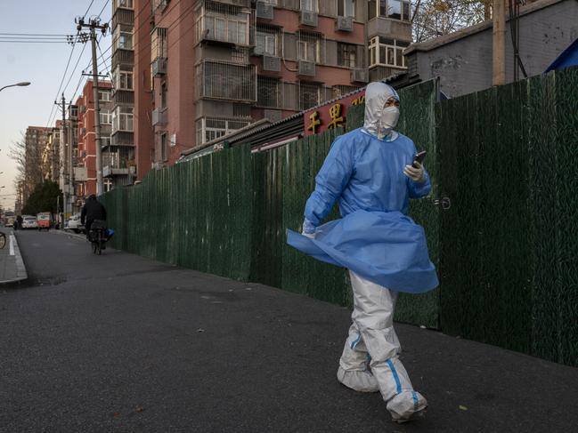 An epidemic control worker wears a protective suit as he walks by a barricade outside a community under lockdown to prevent the spread of Covid-19. Picture: Getty Images.