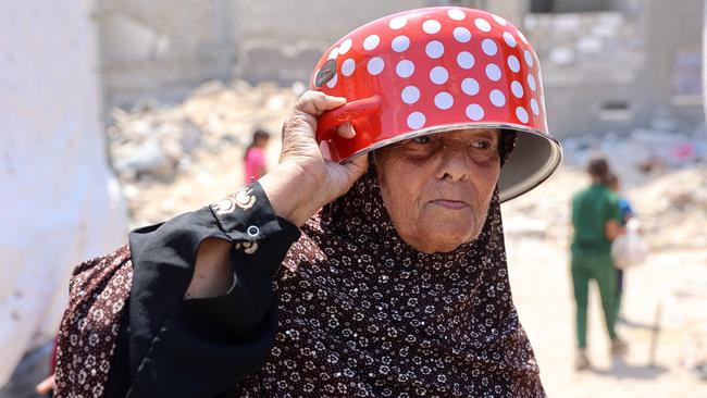 An old Palestinian woman uses a pot to protect her head from the sun on her way to a food distribution point in the Jabalia refugee camp in northern Gaza Strip on August 21, 2024, amid the ongoing conflict in the Palestinian territory between Israel and Hamas. (Photo by Omar AL-QATTAA / AFP)