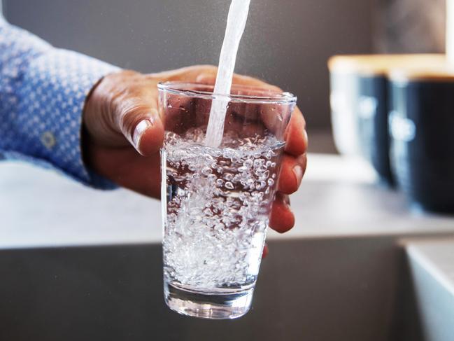 Mature male hand  pouring a glass of water from tap in the kitchen sink