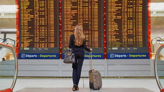 ESCAPE: AIRPORT STORIES, GABBI JOHNSTON - Young elegant business woman with hand luggage in international airport terminal, looking at information board, checking her flight. Cabin crew member with suitcase. Picture: Istock