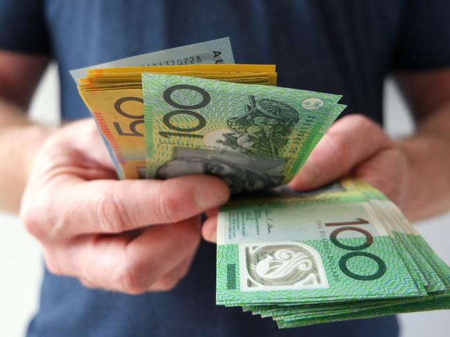 A man counting Australian dollar bills. A picture that describes buying, paying, handing out money, or showing money. Australian cash money generic