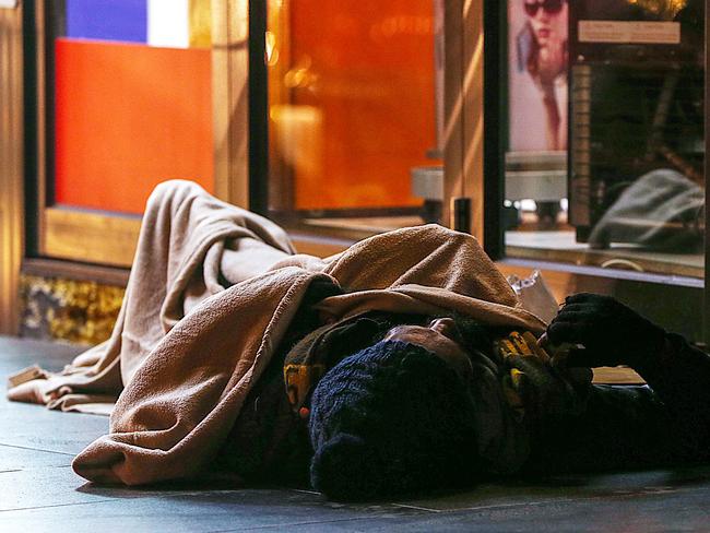 A man asleep on the path in Flinders Street. Picture: Ian Currie