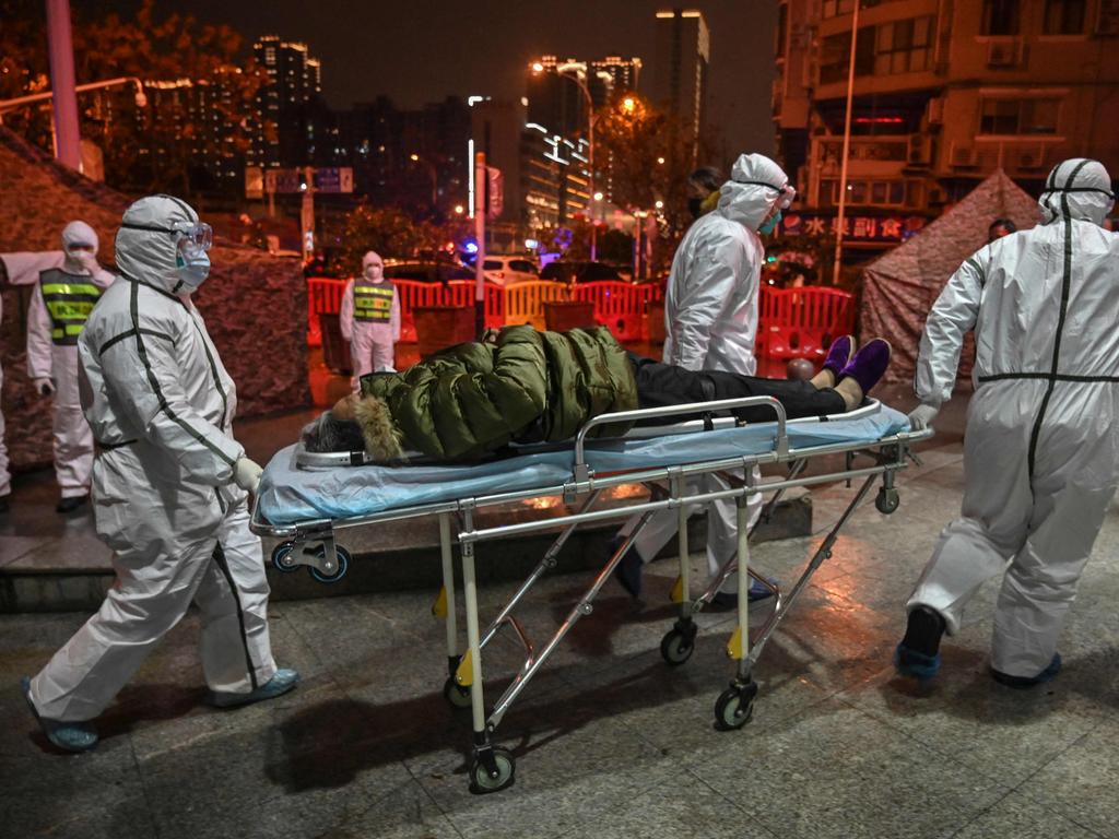 Medical staff members wearing protective clothing to help stop the spread of a deadly virus which began in Wuhan arrive with a patient at the Wuhan Red Cross Hospital. Picture: AFP