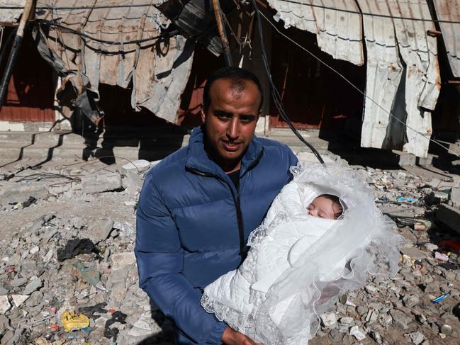 A man poses for a picture with his newborn baby on the rubble of building destroyed in Israeli bombing in Rafah in the southern Gaza Strip. Picture: AFP