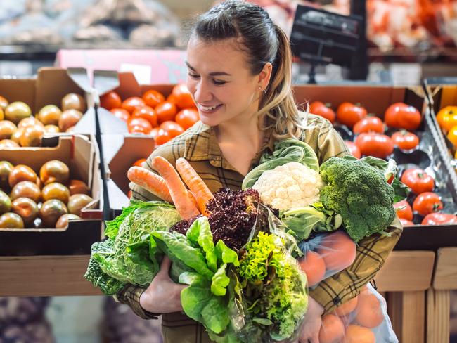 Woman in the supermarket. Beautiful young woman shopping in a supermarket and buying fresh organic vegetables. The concept of healthy eating. Harvest generic istock