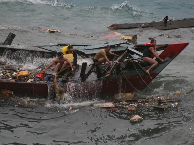 Navy personnel pull survivors and bodies from the water after a boat crashed into Christmas Island in 2010. Picture: Amy Rossbach and Allan Krepp