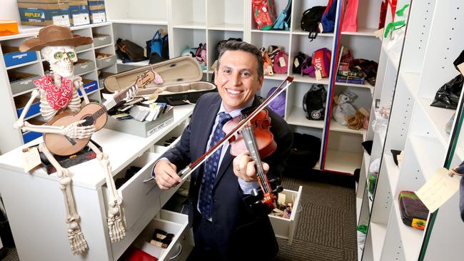 Lifestyle and Community Services chair Peter Matic jams a singing skeleton, one of the thousands of items of lost property handed into Brisbane City Council since July. Picture: Steve Pohlner