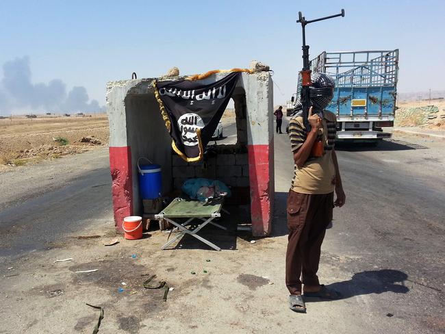 An ISIS militant stands guard at a checkpoint captured from the Iraqi Army outside Beiji refinery. AP Photo, File