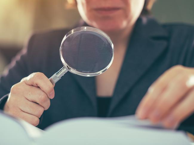 Business corruption audit inspection concept, female inspector using magnifying glass; tax generic