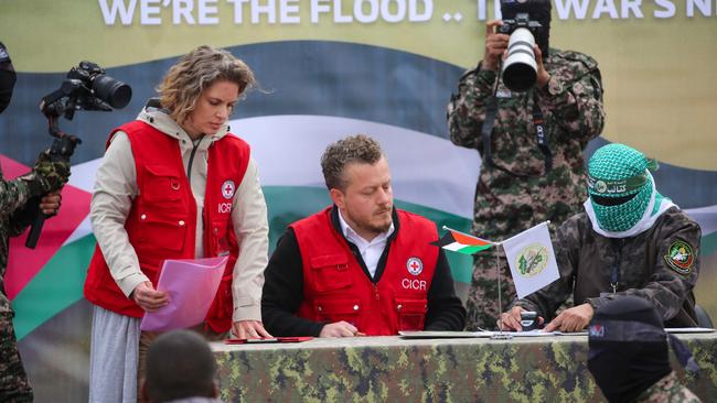 A member of the Red Cross team signs documents before Palestinian Hamas fighters hand over three Israeli hostages in Deir el-Balah. Picture: AFP.