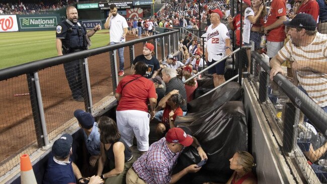 Fans take cover inside the dugout after gunfire was heard.