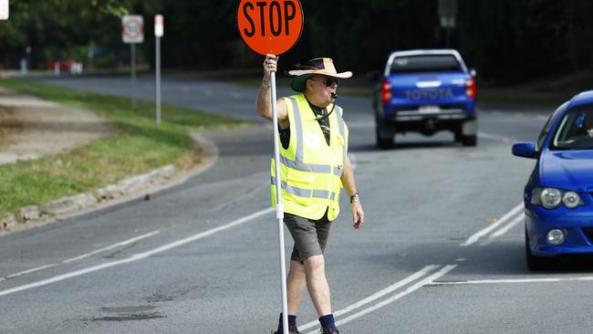 Lollipop man Bill Dudley helps students from Holy Cross School and Smithfield State High School cross the road on Cheviot Street, Smithfield. Picture: Brendan Radke