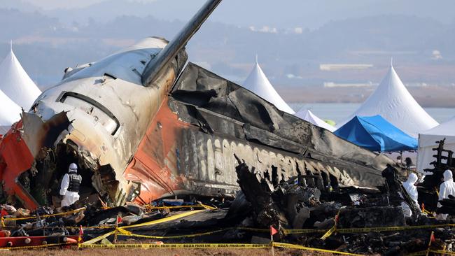 Officials from the Ministry of Land, Infrastructure and Transport's Aviation and Railway Accident Investigation Committee scour the site where 179 people died in the worst aviation disaster on South Korean soil. Picture: YONHAP/AFP