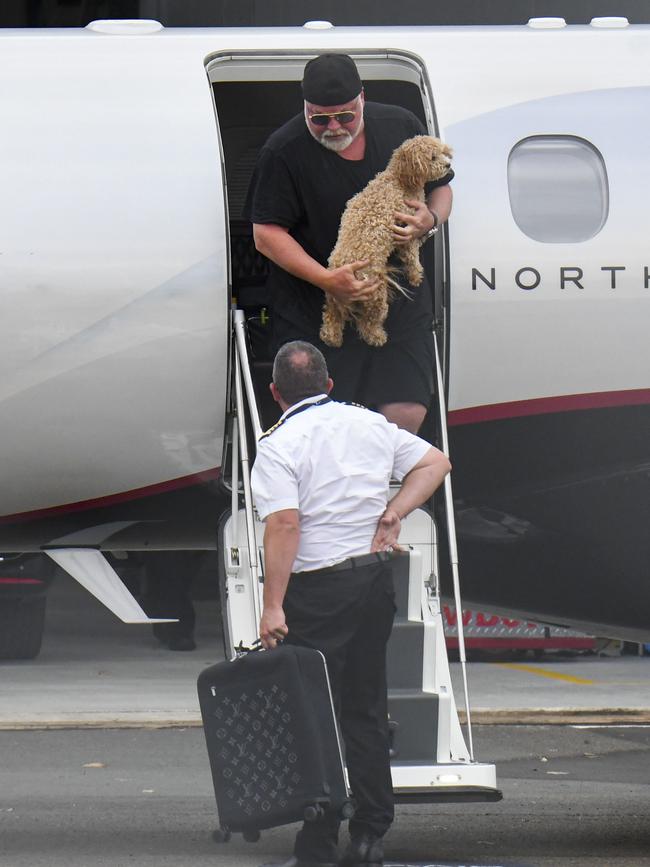 Radio king Kyle Sandilands leave the plane carrying the couple’s puppy, Tacita. Pictures: Media Mode