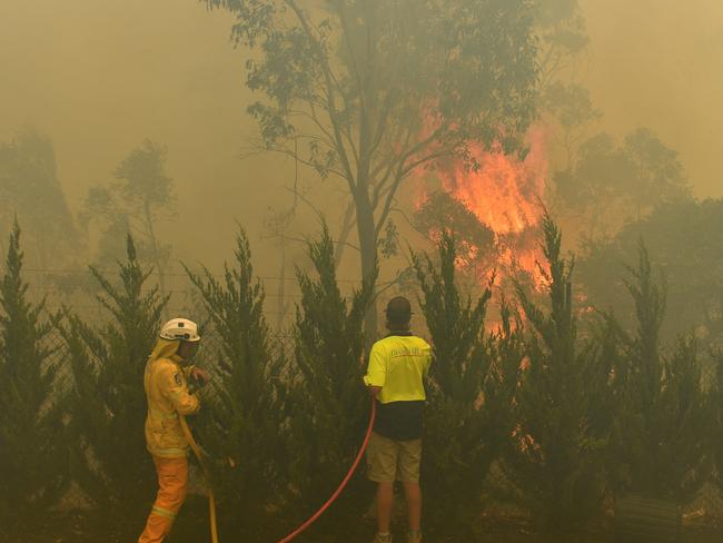 Worker try to put out a bushfire behind a row of factories near West Queenbeyan, 10km west of Canberra, Thursday, January 23, 2020. (AAP Image/Mick Tsikas) NO ARCHIVING