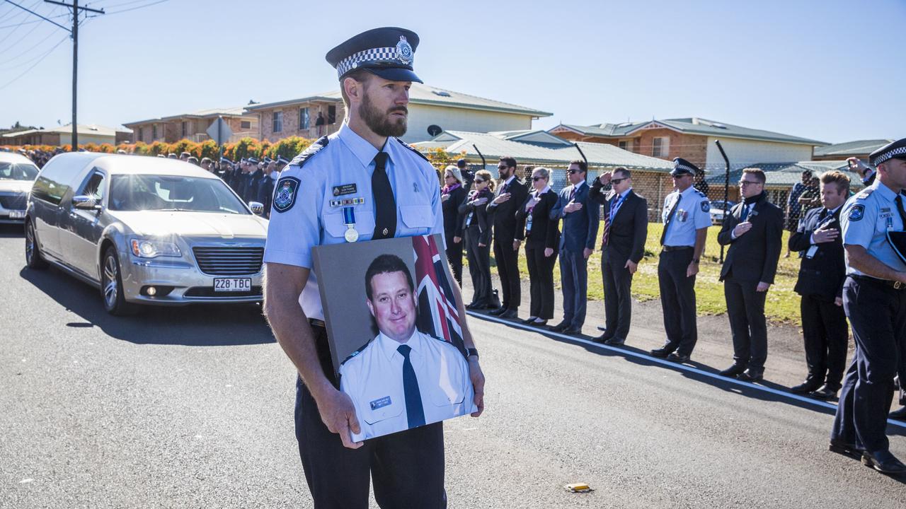 Sergeant Glen Thomas carries a photograph of Senior Constable Brett Forte during the funeral procession in Toowoomba. Picture: AAP, Glenn Hunt