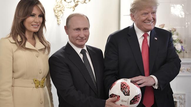 Melania Trump, Vladimir Putin and Donald Trump, pose with a soccer ball Mr Putin gave the Trumps. Picture: Kremlin Pool Photo via AP.