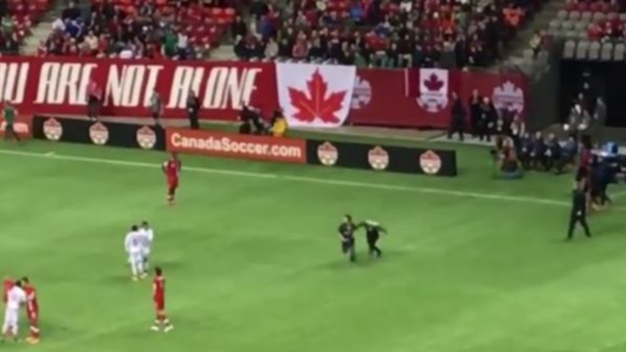 Moment pitch invader wielding pink flare is tackled by security