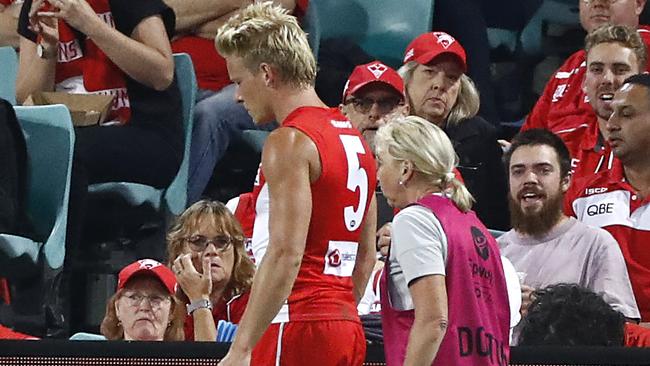 A deflated Isaac Heeney leaves the field in the hands of a Swans trainer. Picture: AFL Photos/Getty Images