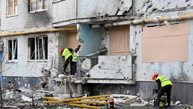 Communal services workers board up holes in walls and broken windows at a residential building damaged by shelling, in Kharkiv, on April 14. Picture: AFP.