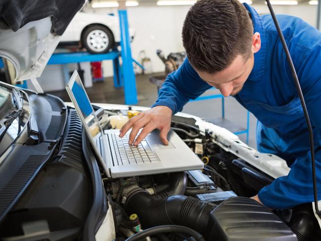 Generic mechanic using laptop on car at the repair garage. Townsville