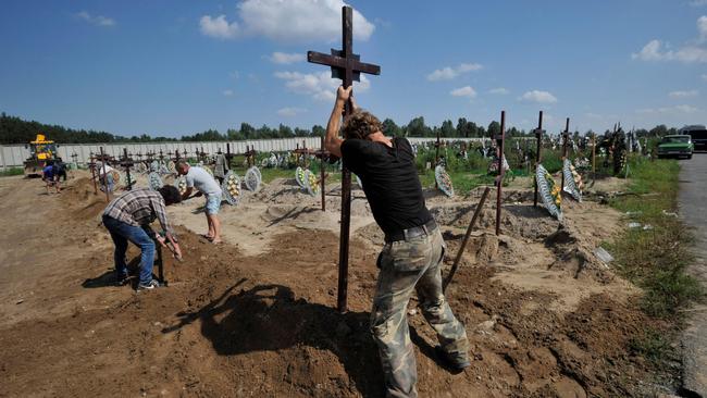 Coffins are buried after the funeral ceremony for unidentified people in Bucha. Picture: AFP