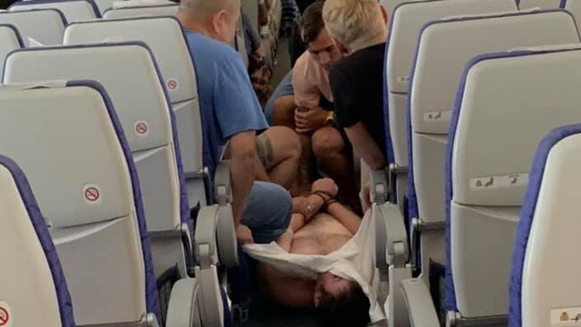 The man is restrained by fellow passengers. Picture: Rico David Garilli/Facebook