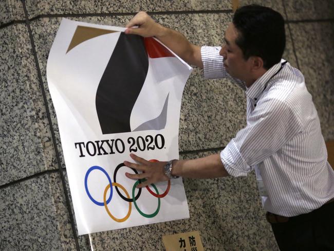 The poster with a logo of the 2020 Olympic Games is removed from a wall in Tokyo.