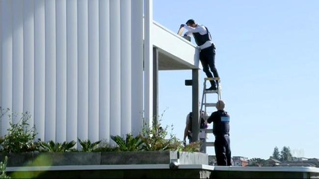 Police are seen searching the guttering of John Ibrahim’s Dover Heights home.